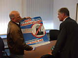 Johann Kruth zeigt Hans Hansen das Plakat der BI mit der Aufforderung Einwendungen einzureichen